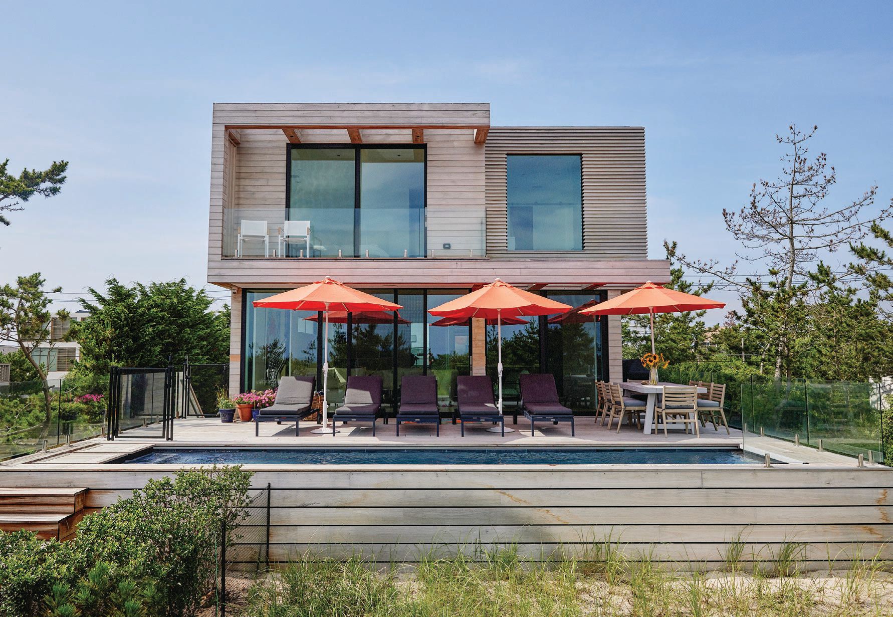 Dotted with cheerful umbrellas, the clean lines of the home’s exterior designed by Rocco Lettieri give its residents a clear view straight to the water. PHOTOGRAPHED BY ZEV STARR-TAMBOR