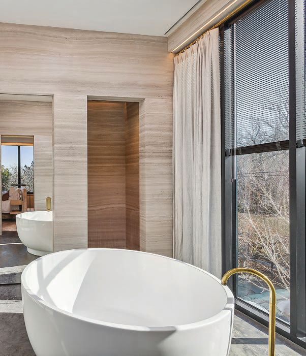 the primary bedroom features an en suite bathroom with a luxurious soaking tub. PHOTO BY RISE MEDIA/COURTESY OF DOUGLAS ELLIMAN